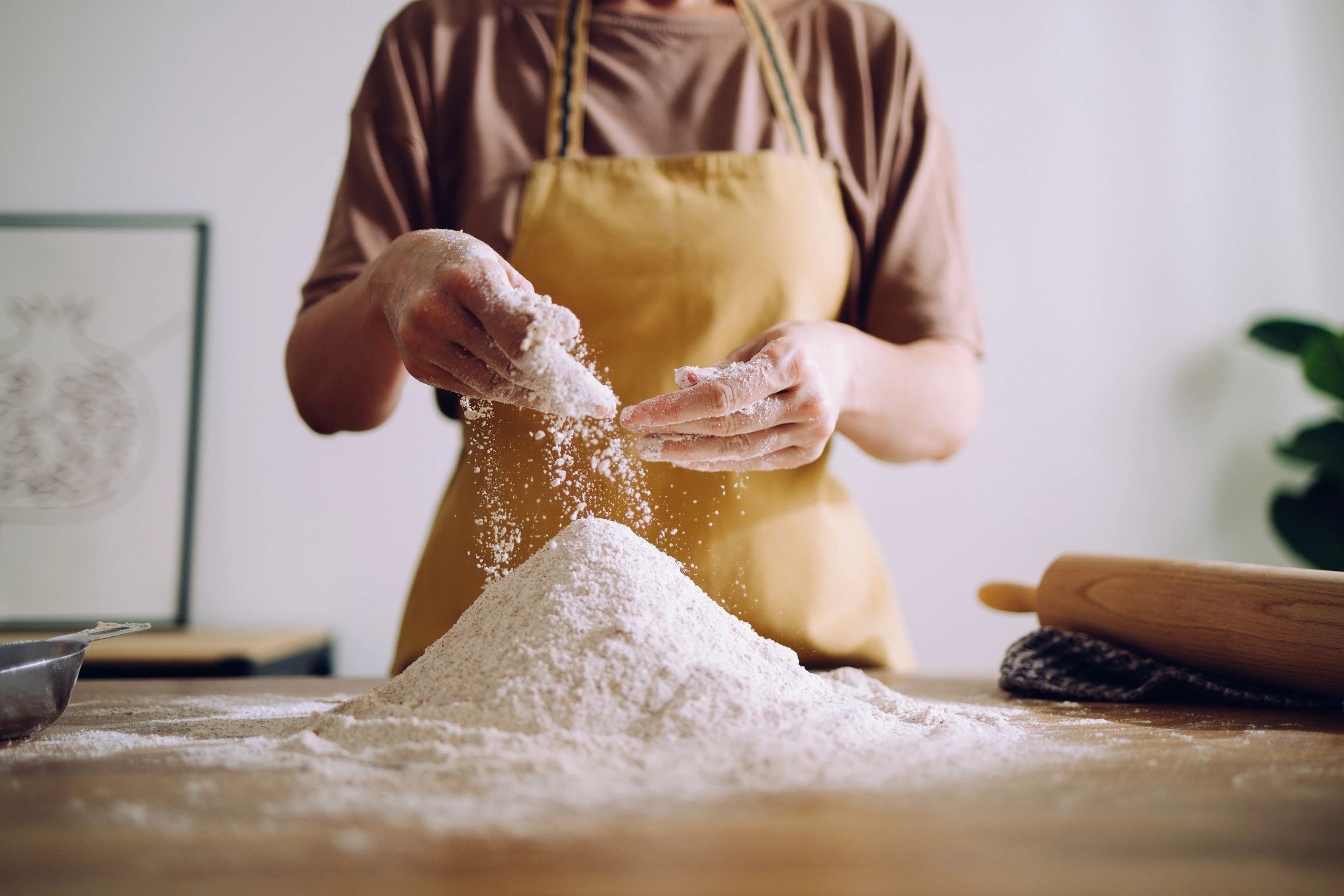 Hands dusting flour while preparing dough for baking