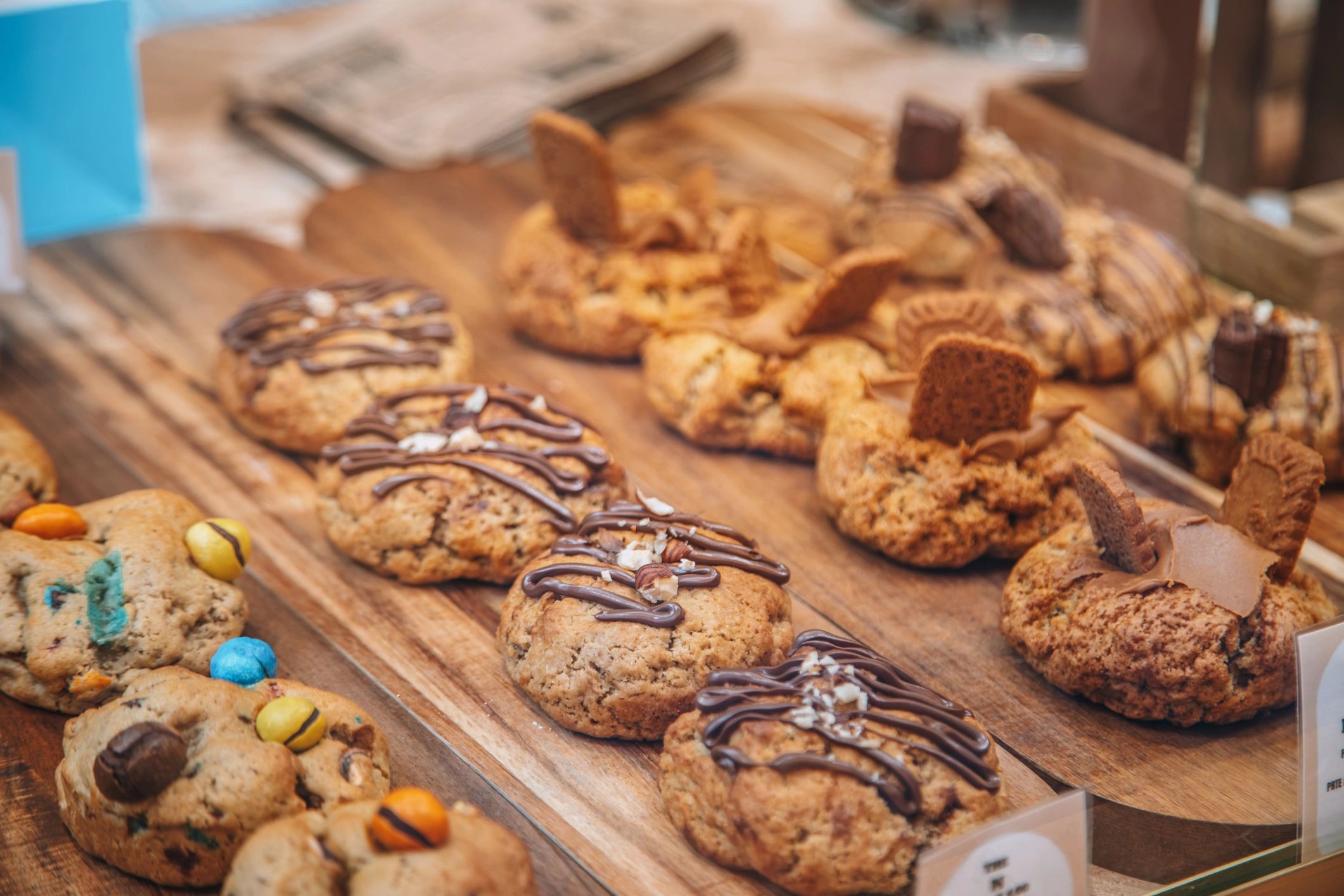 Freshly baked cookies with chocolate drizzle on a wooden tray